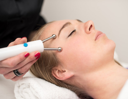 Young woman lying on massage table receiving face massage. Beauty treatment concept.