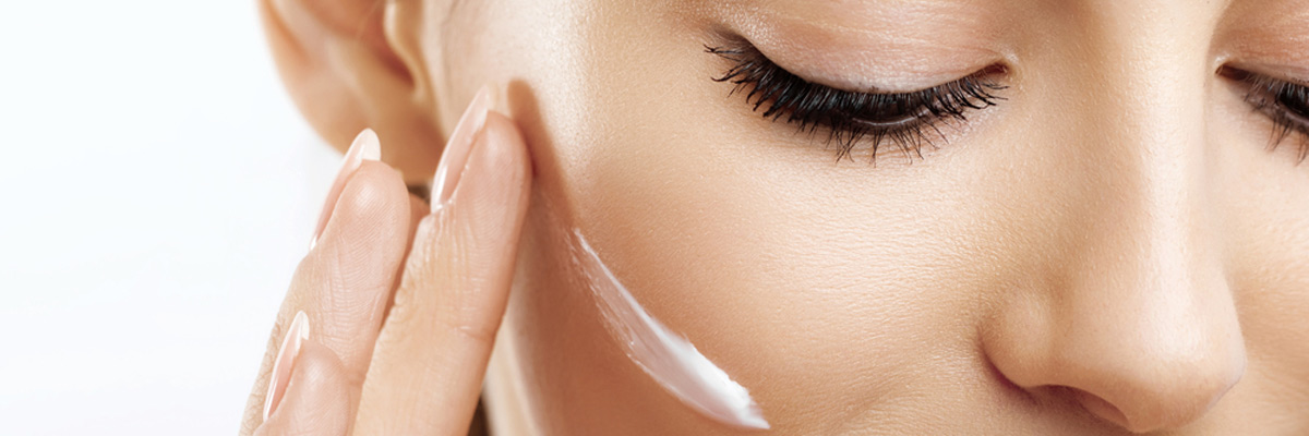 happy young woman applying cream to her face