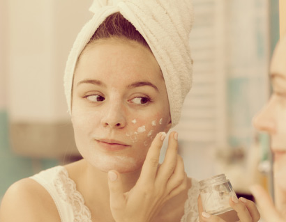 Woman applying mask cream on face