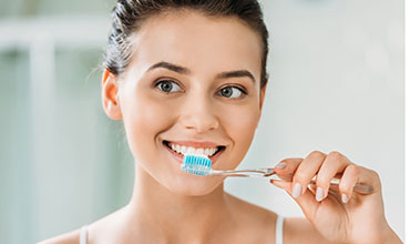 Beautiful smiling girl brushing teeth in bathroom