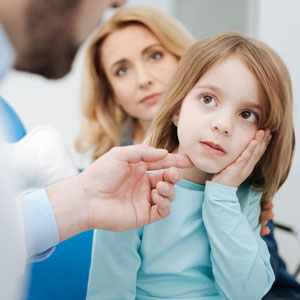 Little upset child telling the doctor about the pain