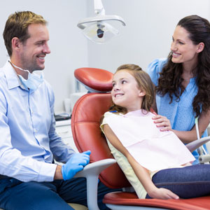 Dentist interacting with mother and daughter