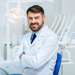 Positive bearded dentist smiling with arms crossed