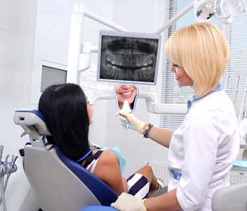 Image of a dentist show patients teeth after applying veeners