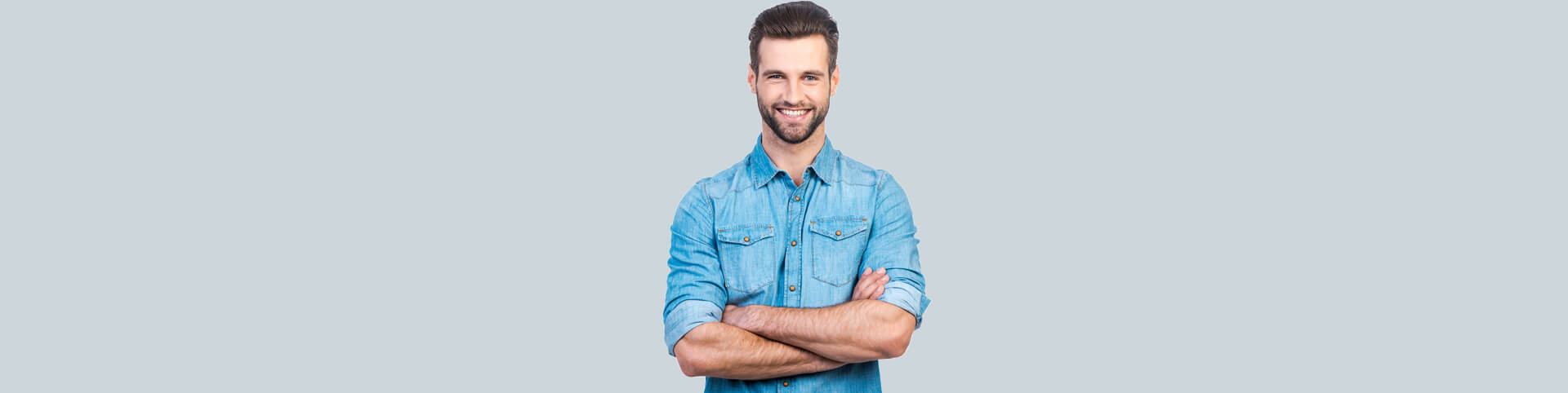 Handsome man smiling with hands crossed in light background