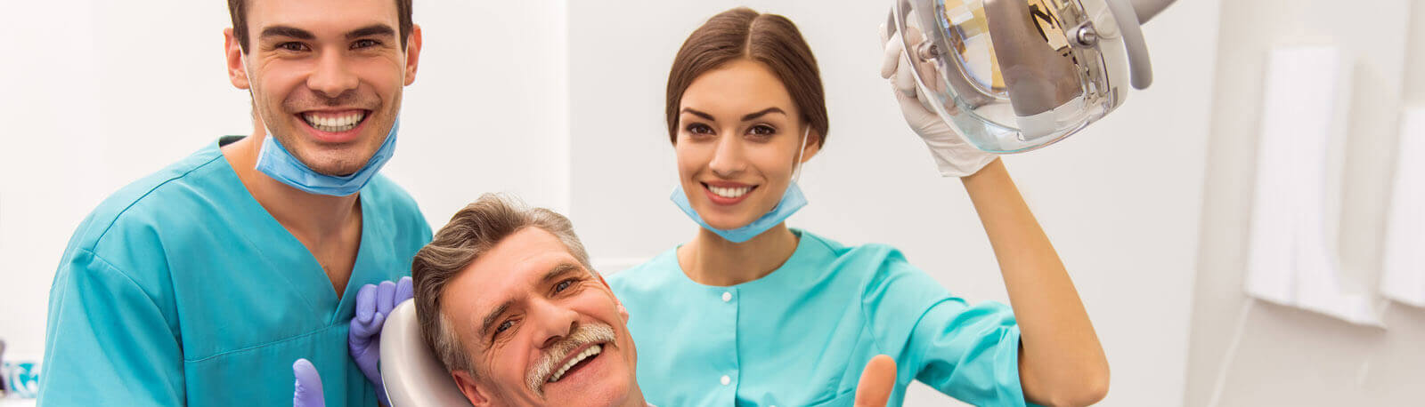 Young doctor dentist and his assistant, elderly patient smiling and looking at the camera