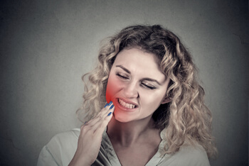 Woman suffering from toothache touching her cheek