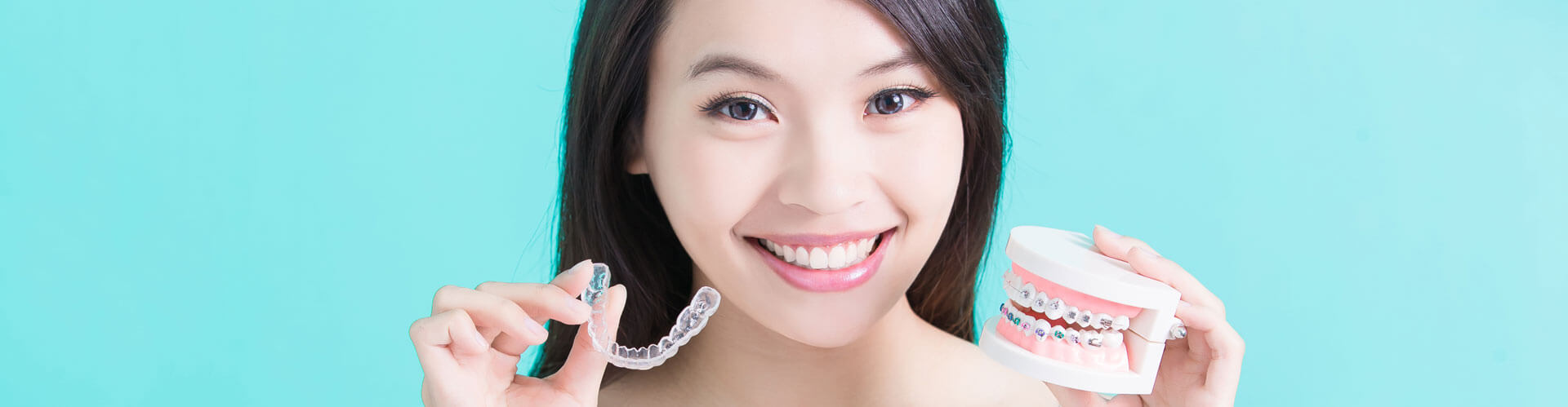 Happy smiling woman holding invisalign braces in blue background
