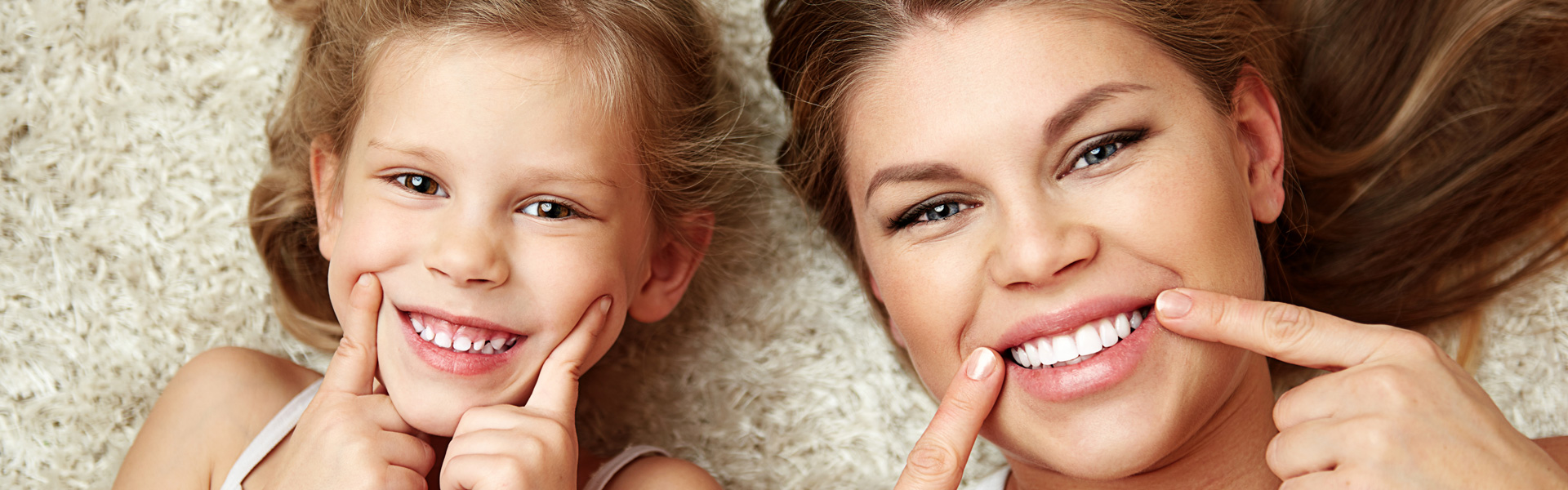 Beautiful daughter with mom showing their healthy white smile