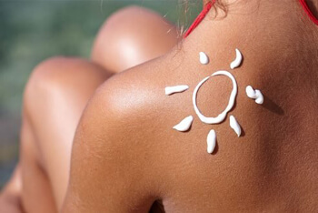 Cropped image of woman's skin with cream applied on her skin showing symbol of the sun