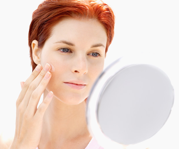 Young woman looking at her face in a mirror