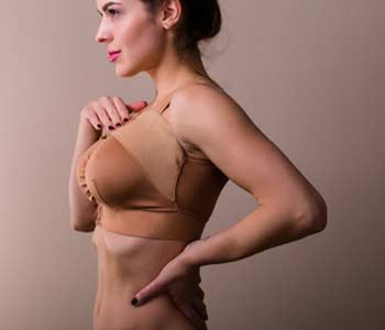 Young woman wearing a compressing bra after a breast augmentation surgery